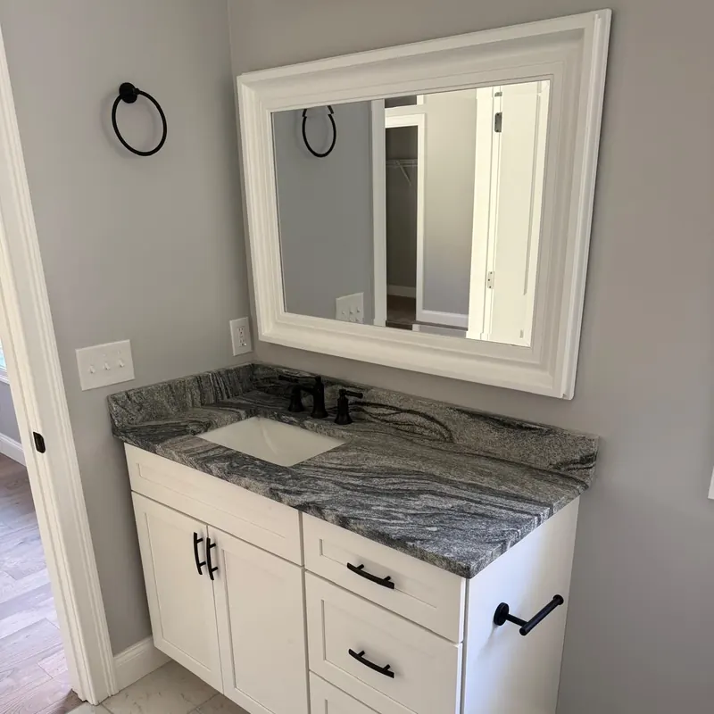 Bathroom vanity with a natural stone countertop and white cabinetry in a New Hampshire home
