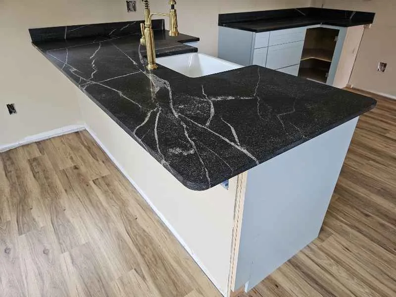 Black granite island with bold white veining and light blue-gray cabinets