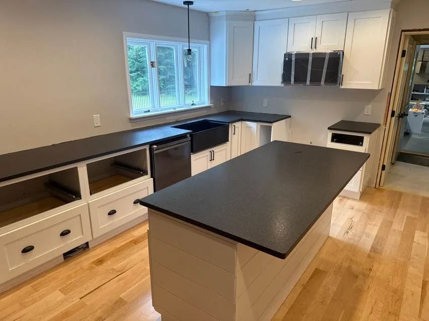 Black Pearl granite countertops with farm sink and island installed in a New Hampshire kitchen with white shaker cabinets