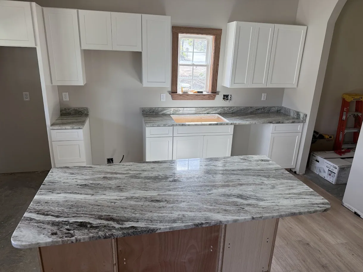 Bold veining granite kitchen island and perimeter countertops with white shaker cabinets — Precision Granite Works NH