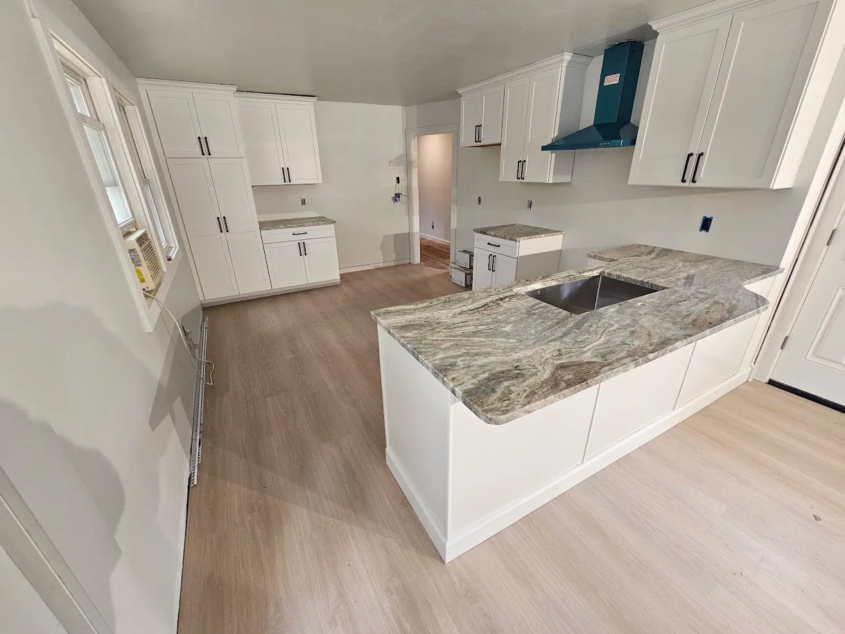 Bold veining granite peninsula with undermount sink cutout and white cabinets — fabricated by Precision Granite Works NH