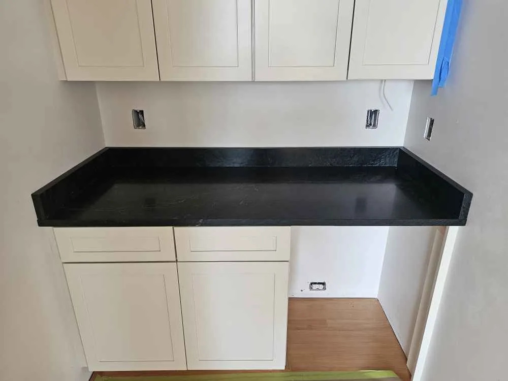 Dark granite countertop and backsplash beneath white cabinets