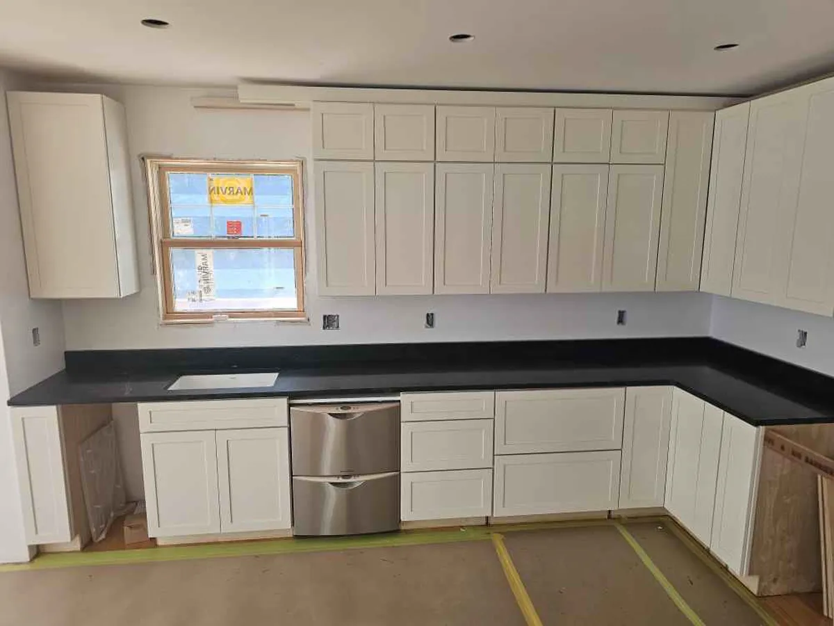 Dark granite L-shaped perimeter countertop with white shaker cabinets — installed by Precision Granite Works NH