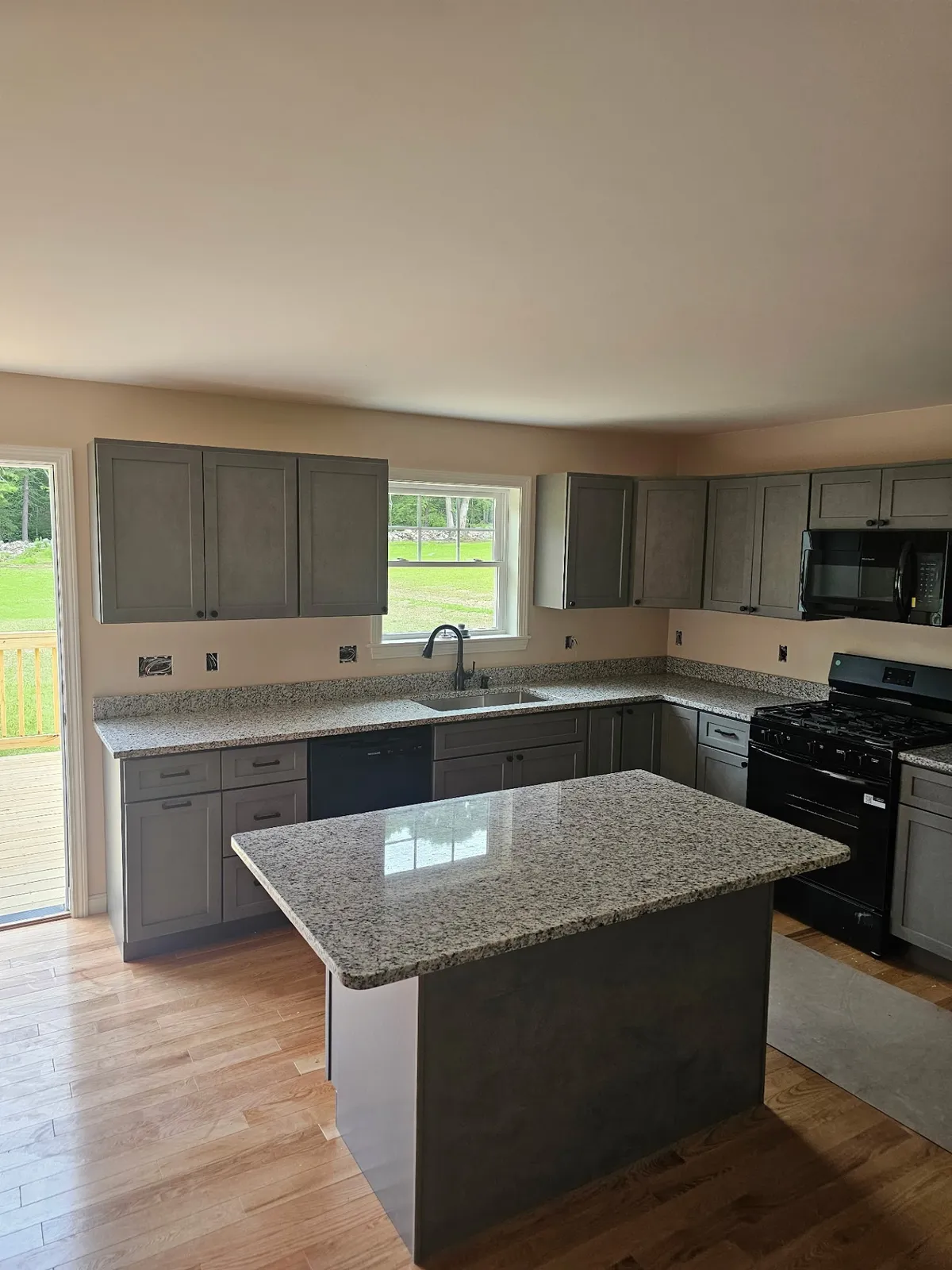 Granite kitchen island against existing gray cabinets in a New Hampshire home