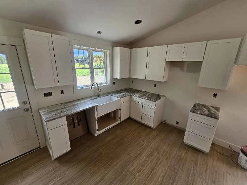 Gray and brown patterned countertop in a white kitchen renovation with a farmhouse sink