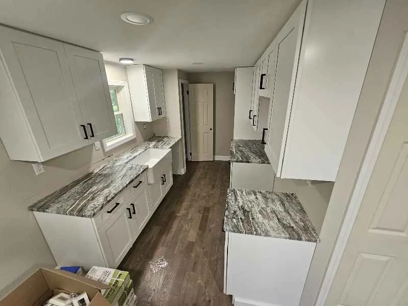 Gray veined kitchen countertops running along both sides of a white kitchen