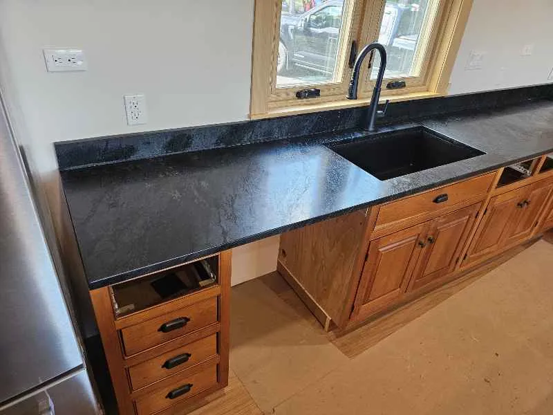 Honed black soapstone kitchen countertops installed over warm wood cabinets