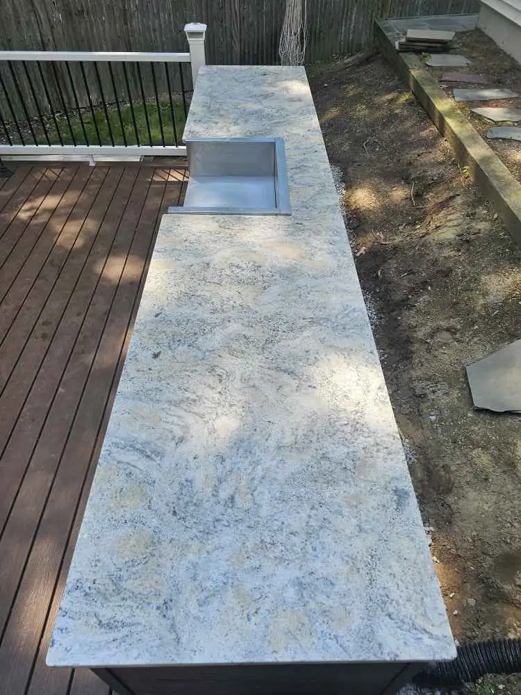 Polar White granite outdoor countertop with a stainless steel sink above a deck.