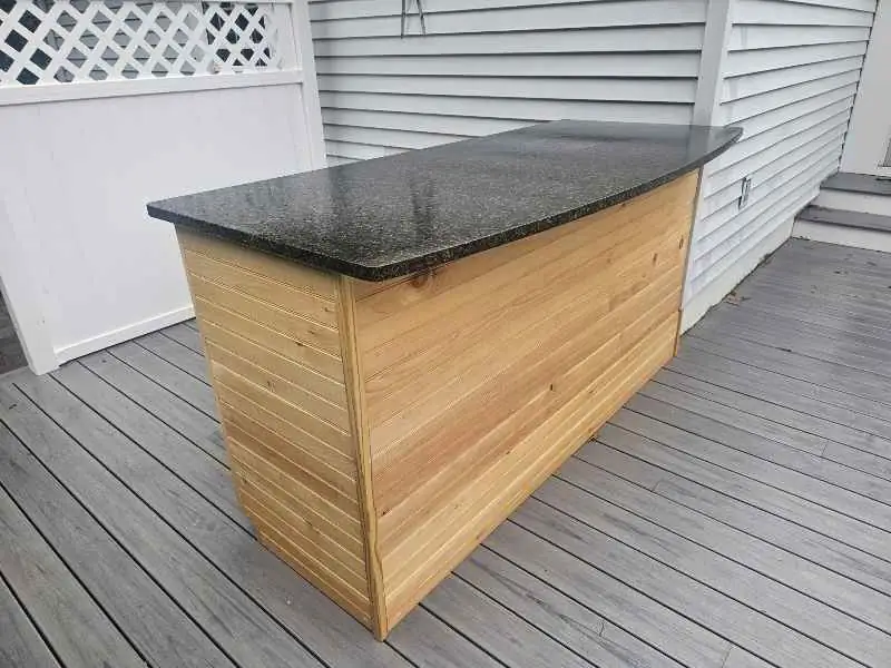 Dark Uba Tuba granite outdoor bar top above a wood-clad base.