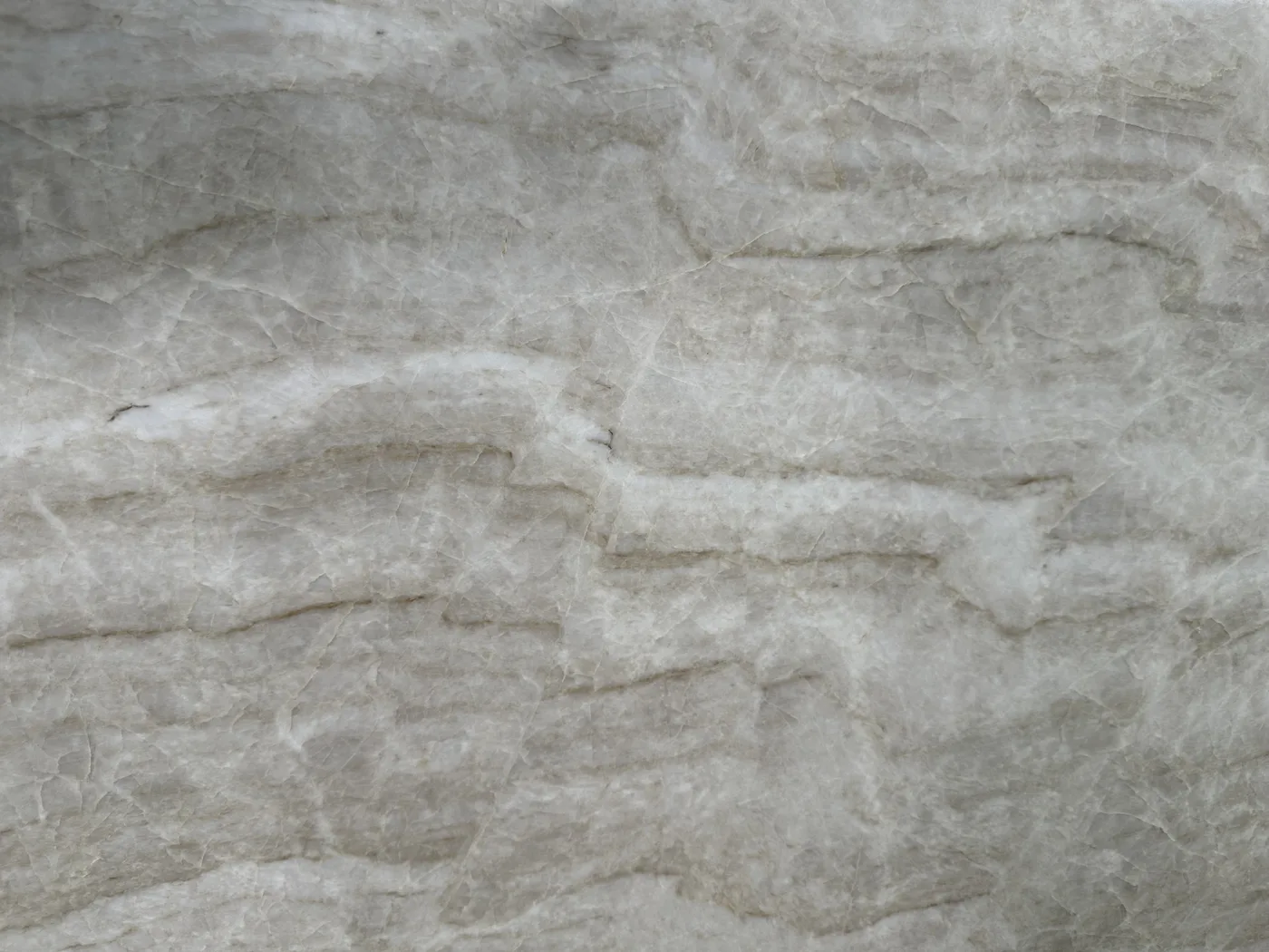 Close view of cream and gray natural stone with layered veining and subtle color variation