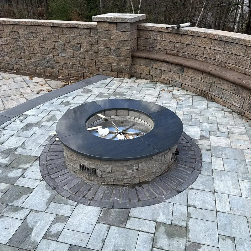 Custom black granite cap on outdoor stone fire pit surround — precision-cut and fabricated by Precision Granite Works in New Hampshire