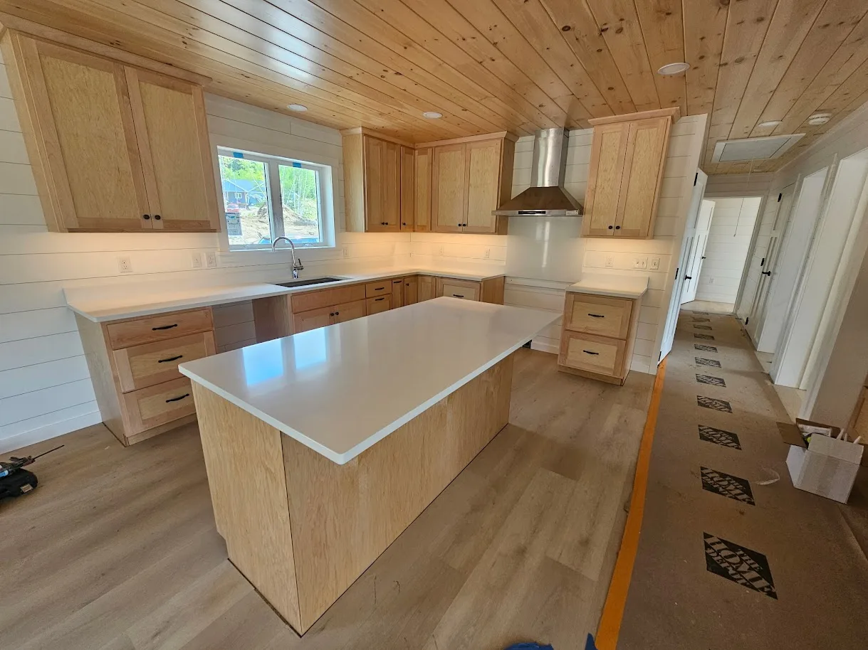 Clean white quartz kitchen island with subtle movement and natural wood cabinets — installed by Precision Granite Works NH