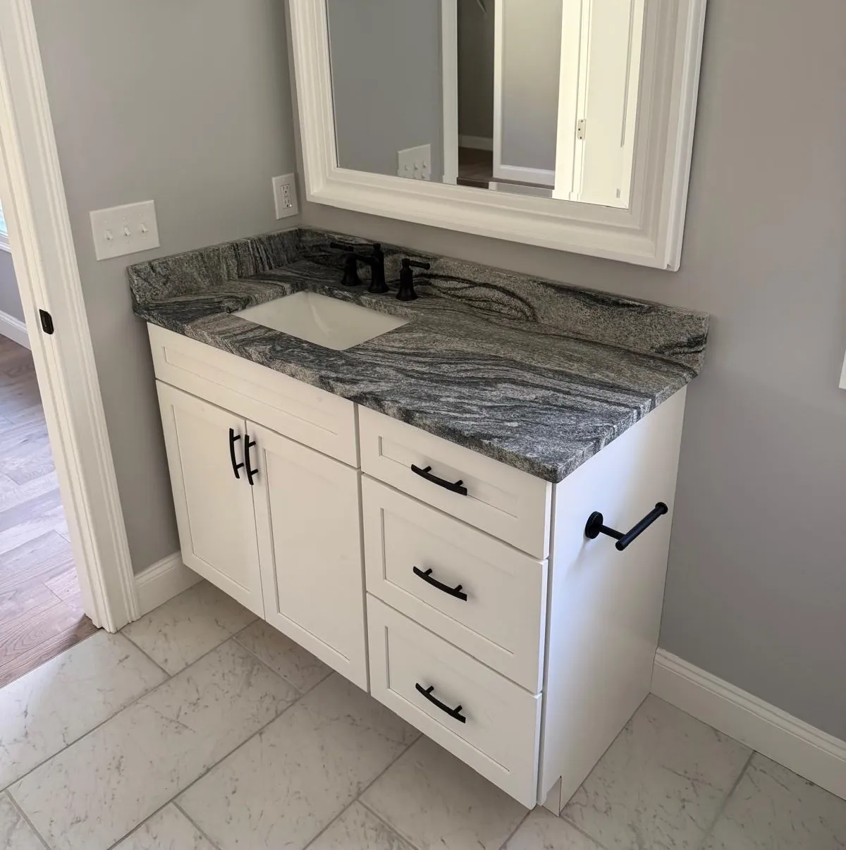 Bathroom vanity top fabricated from a granite remnant slab — dramatic swirl pattern with undermount sink, installed by Precision Granite Works in New Hampshire