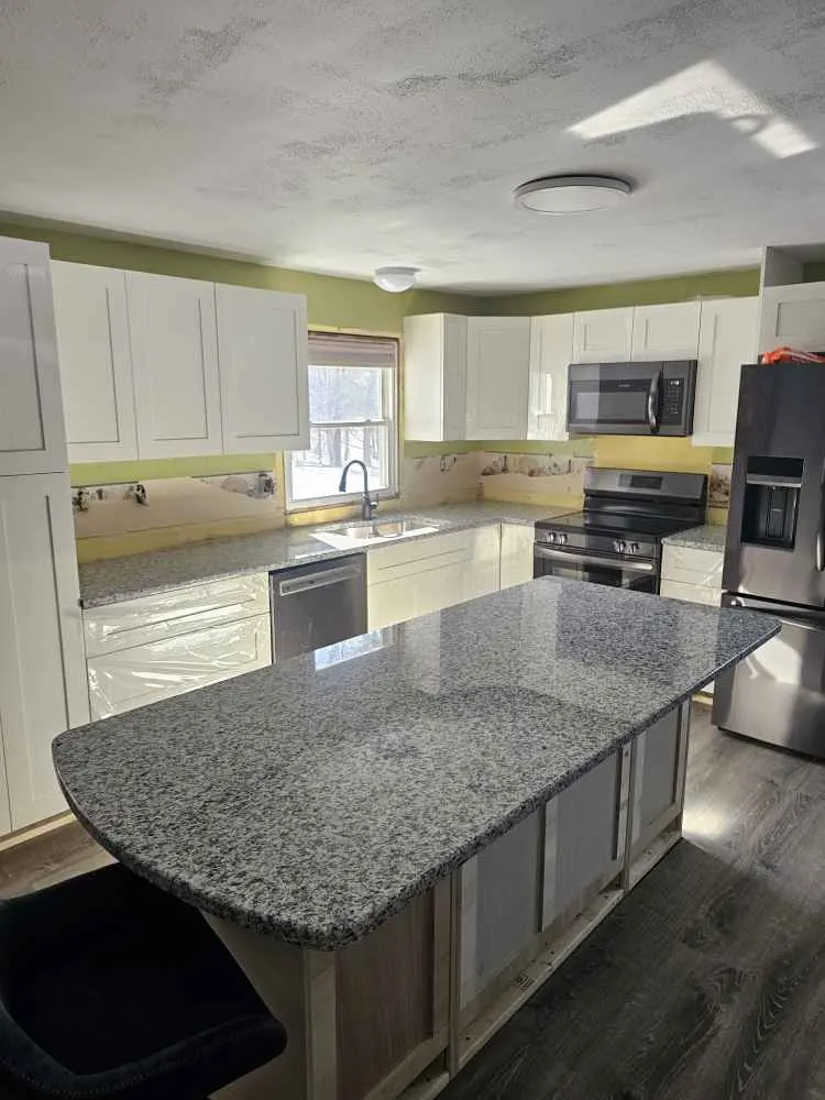 Speckled granite kitchen island with a broad rounded seating end and straight cabinet base