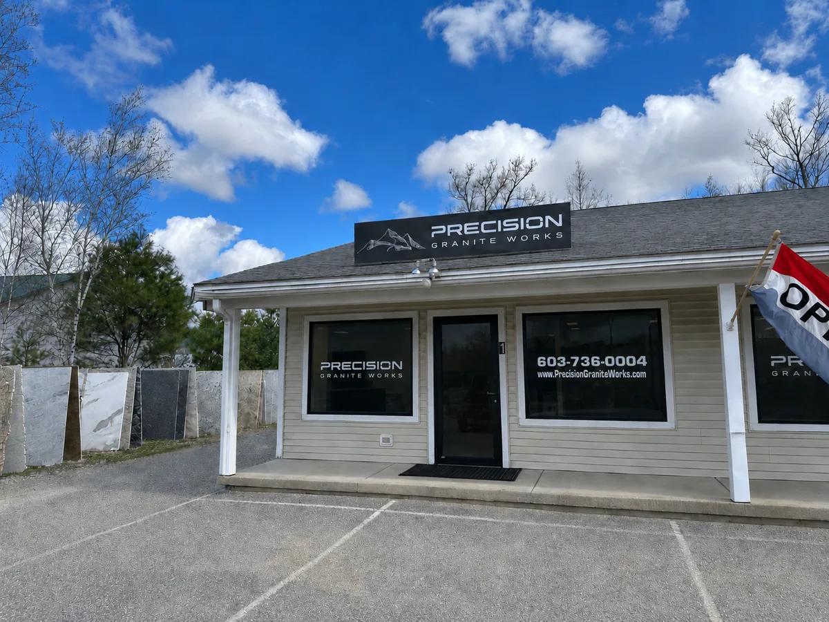 Precision Granite Works showroom exterior in Epsom, NH — granite and quartz slabs visible outside