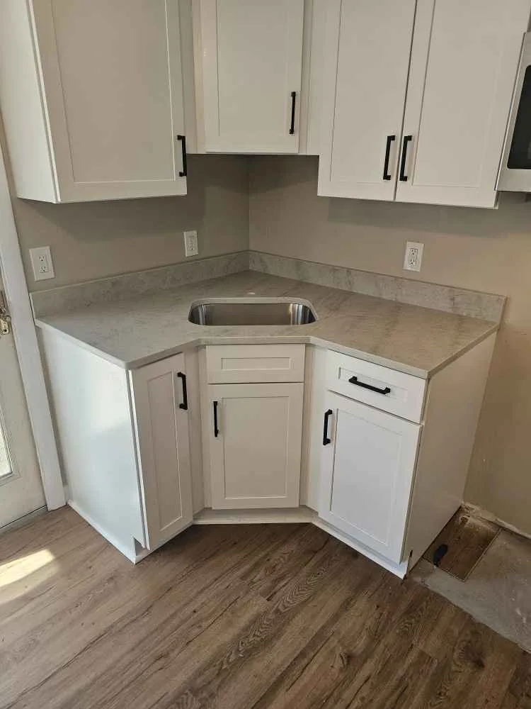 Taj Mahal quartzite corner countertop with undermount sink and white shaker cabinets — fabricated by Precision Granite Works NH