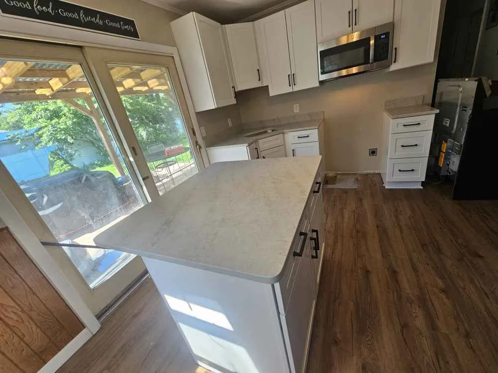Taj Mahal quartzite kitchen with white shaker cabinets and large island — installed by Precision Granite Works in New Hampshire