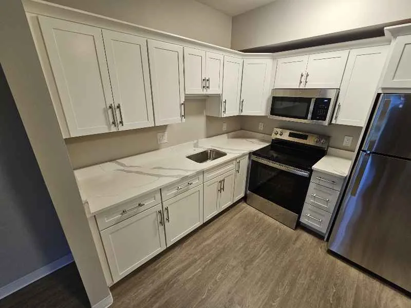Warm white countertop with soft gray veining in a white kitchen with stainless steel appliances
