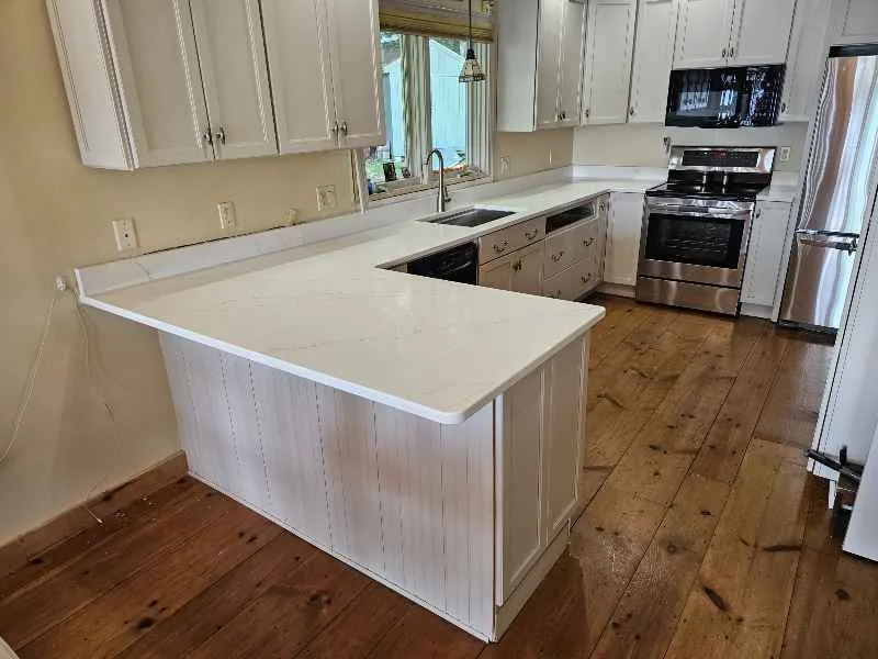 White countertop island and perimeter runs in a finished kitchen