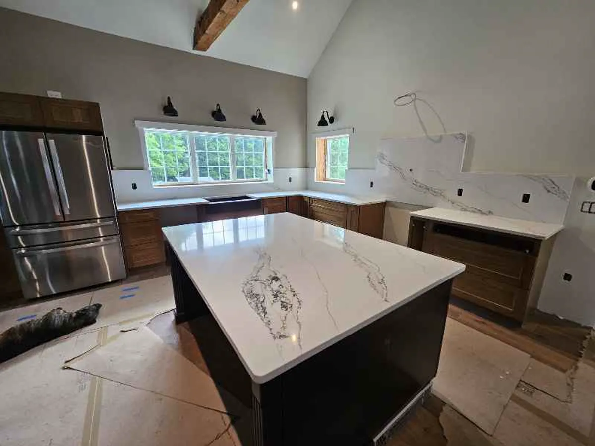 White quartz island with dramatic veining paired with dark wood cabinets and walnut accents — fabricated by Precision Granite Works NH