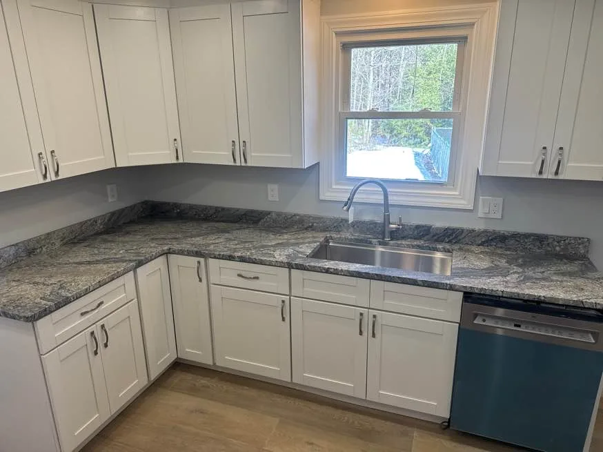 White Wave granite kitchen countertop overlooking snowy woods in a New Hampshire camp home