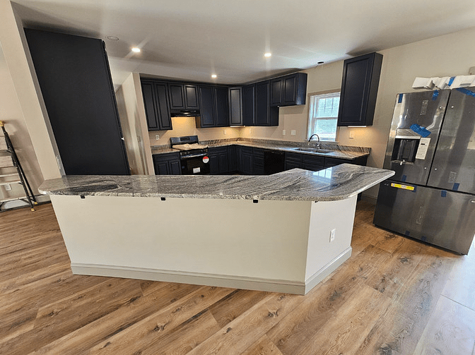 A gorgeous, long grey, white, and black marbled countertop island separating the kitchen from the living room.