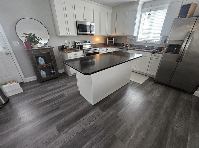 A sleek black custom countertop on white kitchen island cabinets.